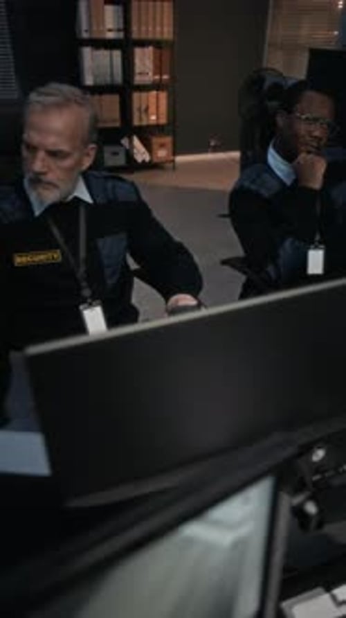 Security Guards Working in Dark Control Room