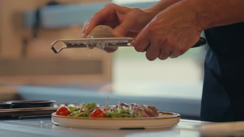 Chef grate cheese on fresh salad and steak, close up