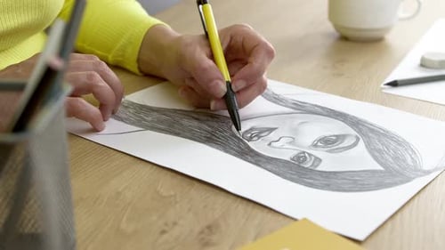 Artist Drawing Portrait with Pencil at Desk