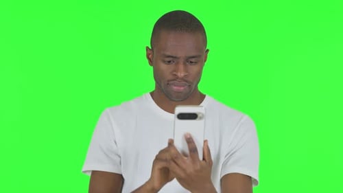 Portrait of African Man using Phone on Green Background