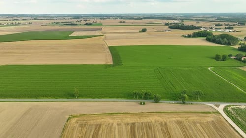 Aerial view of a diverse agricultural landscape with green and brown fields, showcasing the variety