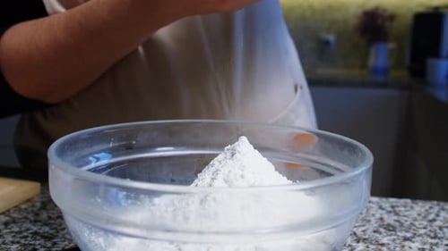 Flour Being Poured into Glass Bowl