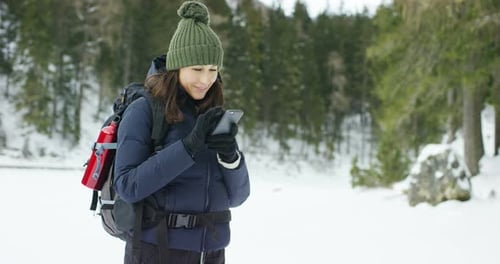Woman Using Phone in Snowy Winter Wilderness
