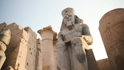 An ancient Egyptian statue outside of a temple.