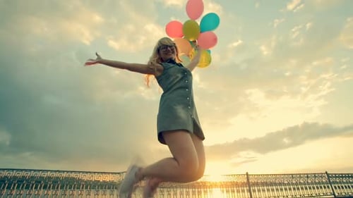 Woman with Balloons Jumping at Sunset