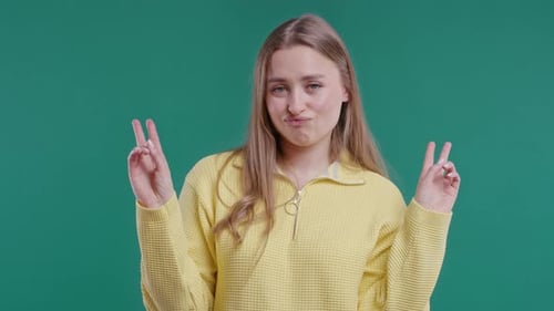 Young Adult Posing Peace Sign in Front of Green