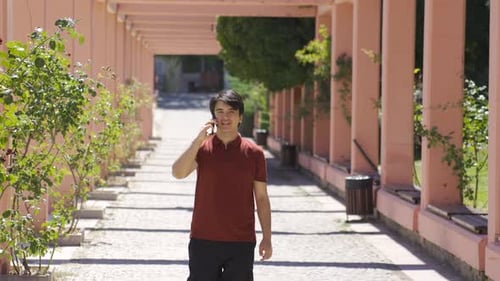 Jeune homme parlant au téléphone en marchant à l'extérieur.