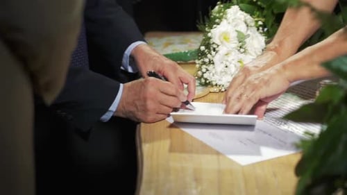 Nahaufnahme von Braut und Bräutigam bei der Unterzeichnung des Ehevertrags auf der Hochzeitsfeier. Unterzeichnung der Ehe