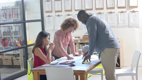 Busy diverse architects discussing blueprints on table in office, slow motion