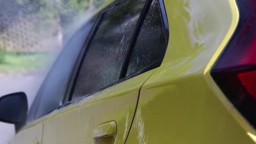 car wash pressure washer on side of car washing off soap