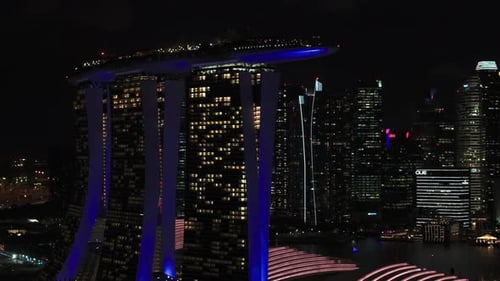 Night drone close up of Marina Bay Sands and Singapore cityscape in background