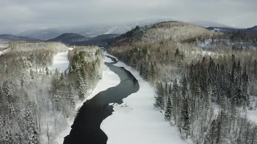 Beautiful 4k cinematic winter landscape. Mountains, river and ski resort. Drone pan left. Sequence 1