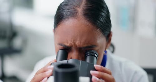Young Adult Woman Looking Through a Microscope