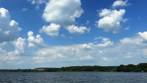 Wunderschöner blauer Sommerhimmel mit weichen weißen Wolken. Aufnahmen über der Flussoberfläche an einem sonnigen Tag.