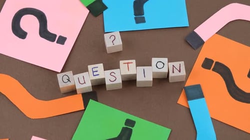 Question Spelled Out with Wooden Blocks and Paper