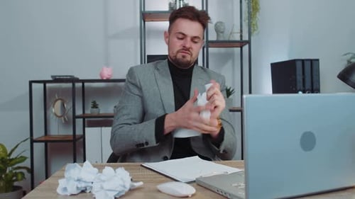 Wütender, wütender Mann, der zu Hause im Büro arbeitet, wirft zerknittertes Papier und hat einen Nervenzusammenbruch bei der Arbeit