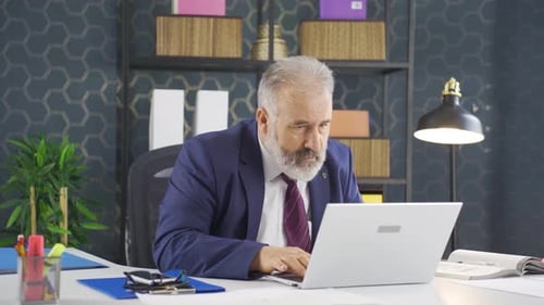 Man working on laptop in office looking stressed