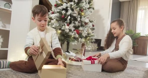 Boy and Girl Opening Christmas Presents at Home