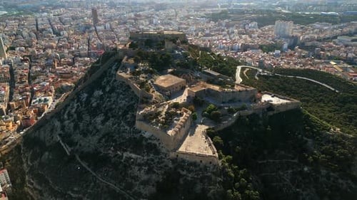 Aerial drone view of the Santa Barbara Castle on the coast of Alicante, Spain with the city on the b