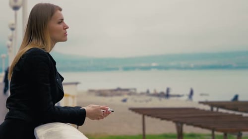 sad woman on a lakeside terrace waiting for a phone call that doesn't come