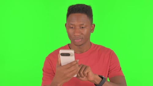 Portrait of African Man using Phone on Green Background