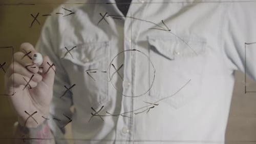Coach Drawing Football or Soccer Game Strategy and Tactics with Black Marker