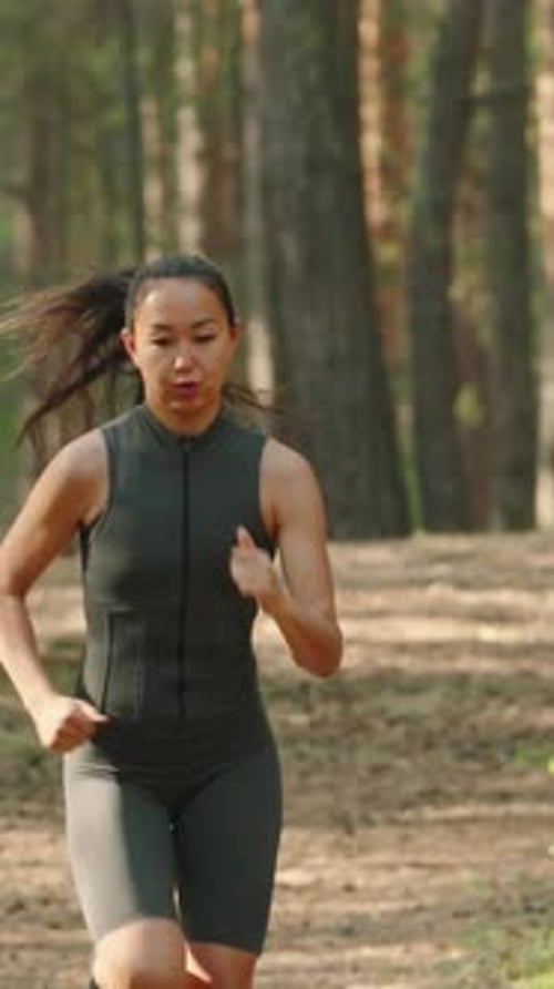 Joven atleta femenina corriendo en el bosque
