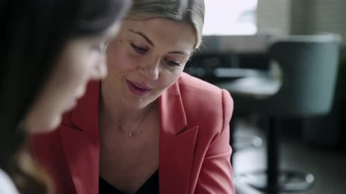 Women Discussing Phone Screen Details Indoors at Workplace