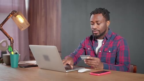 Aufmerksamer Afroamerikaner, der Online-Zahlungen mit Kreditkarte durchführt