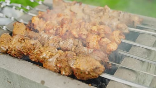 Rauch steigt auf, während Schaschlikspieße im Freien über dem Holzkohlegrill garen