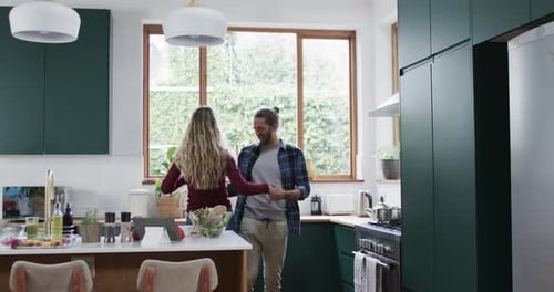 Happy diverse couple dancing in kitchen at home, in slow motion