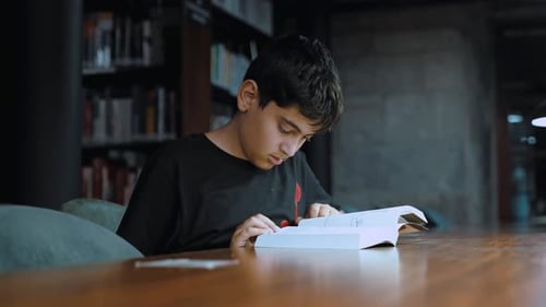 Young Boy Reading a Book in a Library
