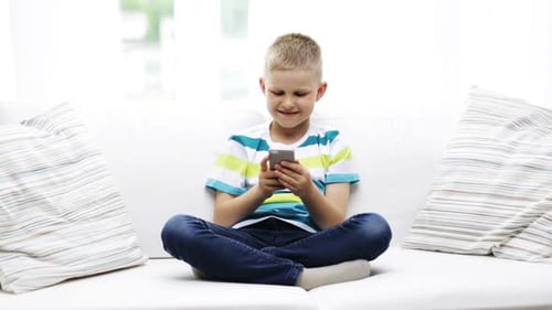 Boy Using Mobile Phone Sitting on Couch Indoors