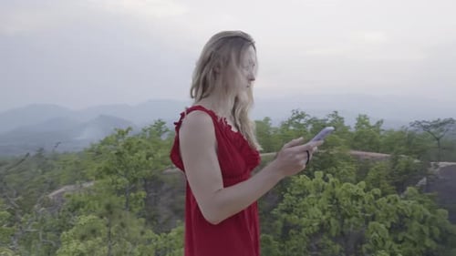 Woman Overlooks Tropical Landscape Using Smartphone