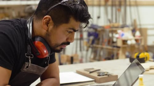 Male Carpenter Working At Laptop In Carpentry Workshop Slow Motion