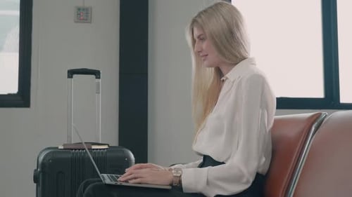 Passenger traveler woman in airport gate working laptop while waiting boarding air before vacation