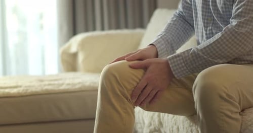 Man Massaging Knee in Living Room