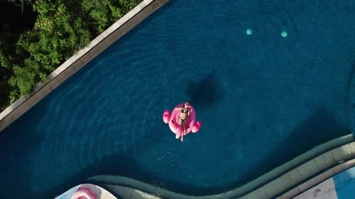 Aerial View of Millennial Passion Woman Swim with Inflatable Pink Flamingo
