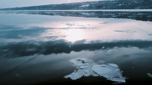 La banquise éclairée par le soleil traverse la surface calme de la rivière pendant l'hiver, vue par Drone