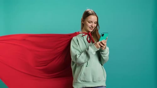 Young Girl Wearing Superhero Costume Texting Friends Using Smartphone