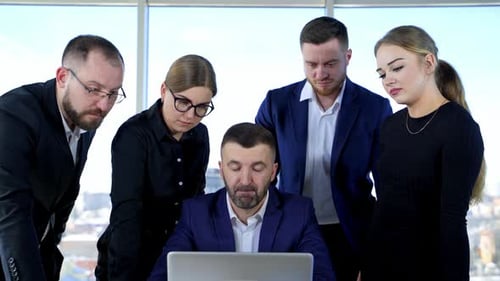 Team Analyzes Data on Laptop in Modern Office