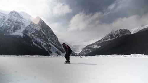 man ice skating on frozen lake luise with mountains on background