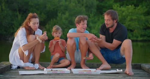 Family Eating Pizza on Dock by Lake