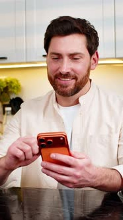 Smiling Man Using Phone in Modern Kitchen