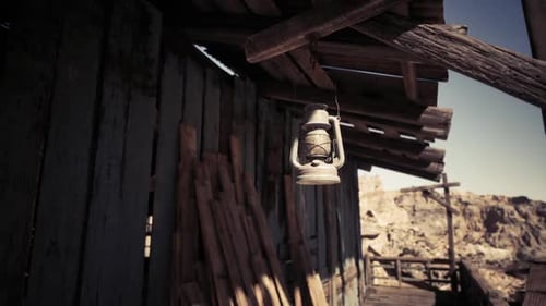 Old Lantern Hanging Outside a Rustic Wooden Cabin in a Desert Landscape