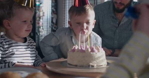 Children Blowing out Birthday Candles with Family