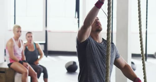 Man Rope Climbing in Gym with Women Watching