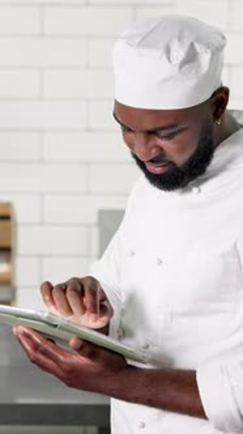Tablet, black man and chef in kitchen, typing and digital app for recipe, food blog and network