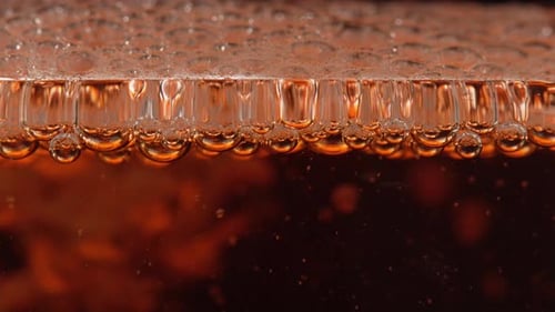 Carbonated ice tea is poured into glass close up. Cool drink with ice tea bubbles macro