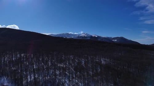 Drone Aerial Video Flying Forward Over Snowy Forest Towards Mountain Horizon in Abruzzo Italy